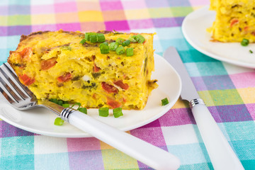 Breakfast casserole with bacon, potatoes, vegetables.