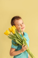 Cute little boy holding a bouquet of flowers. Tulips. Mothers Day. International Women's Day. Portrait of a happy little boy on a white background. Spring.