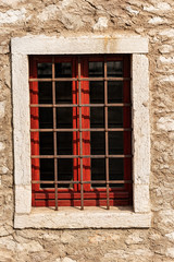 Obraz premium Closeup of an old window with wrought iron security bars on a stone wall. Veneto, Italy, Europe