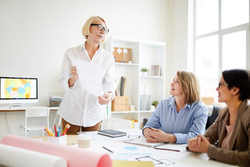 Fototapeta premium Portrait of three successful businesswomen planning work while collaborating on design project in studio