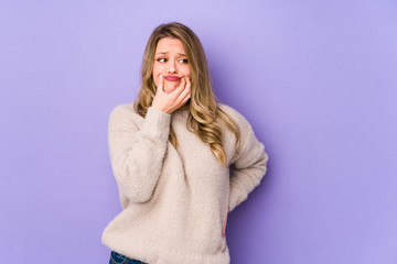 Young caucasian woman isolated on purple background doubting between two options.