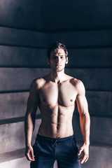 Fototapeta na wymiar Muscular man shirtless. Handsome man with perfect body after training in dark studio.