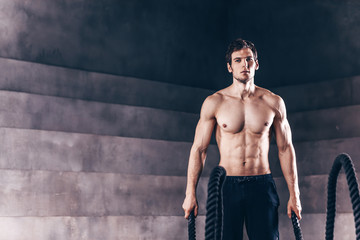 Fototapeta na wymiar Athletic young man with battle rope doing exercise.