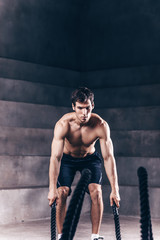 Fototapeta na wymiar Fitness man workout with battle ropes at gym.