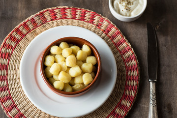Delicious dish of round potato gnocchi accompanied by cheese sauce with the necessary accessories to taste them