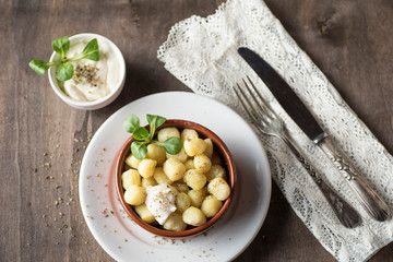 Delicious dish of round potato gnocchi accompanied by cheese sauce with the necessary accessories to taste them