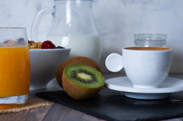 Complete breakfast consisting of coffee with milk, orange juice, fresh fruit, cereals and corn bread toast with olive oil on a wooden surface. Healthy concept.