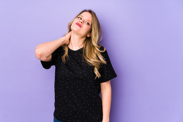 Fototapeta premium Young caucasian woman isolated on purple background having a neck pain due to stress, massaging and touching it with hand.