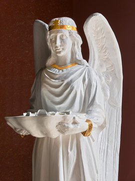 A white painted statue of an angel with golden star, holding a shell with holy water, located at the entrance of Binondo church in Manila, Philippines