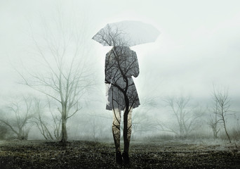 Girl with umbrella standing on the field with trees. Rain. Loneliness. The image with the effect of...