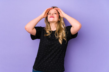 Young caucasian woman isolated on purple background laughs joyfully keeping hands on head. Happiness concept.