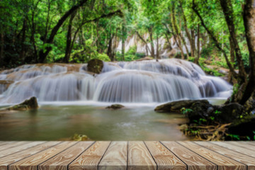 Beautiful waterfall in green forest ,Front view wood table. 