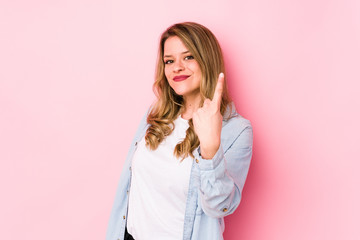 Fototapeta premium Young caucasian woman isolated on pink background pointing with finger at you as if inviting come closer.