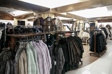 natural fur coats hang on hangers in a store. Sale of winter warm clothes. Turkish shop
