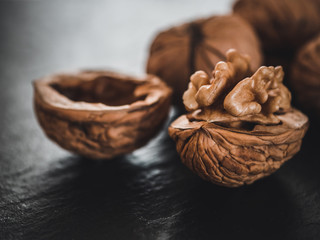 Fototapeta premium Whole walnuts on dark board. Walnut kernels on dark background. Healthy food nuts.