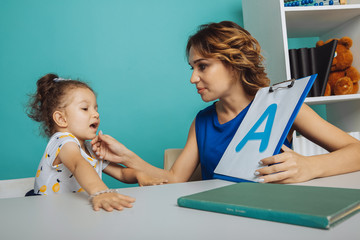 Child with therapist working on pronunciation and sounds together sitting in the class