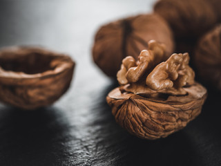 Whole walnuts on dark board. Walnut kernels on dark background. Healthy food nuts.