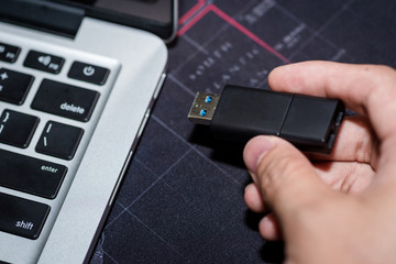 Hand inserting USB flash memory drive plugged into a computer laptop port.