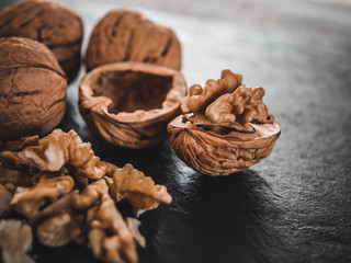 Whole walnuts on dark board. Walnut kernels on dark background. Healthy food nuts.