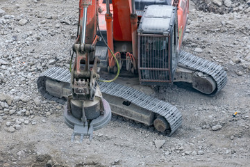 Magnetic crane loading scrap metals on the ruins of a construction site.