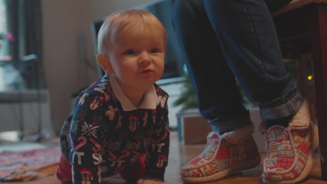 Amazing cute baby infant child crawling on the carpet floor in the room looking forward playing with parents. Family at home.