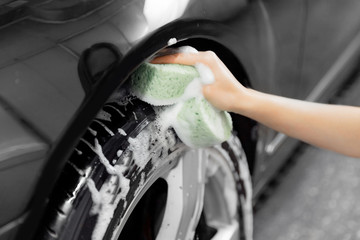 Service car wash express. Girl worker clean tire and rubber wheel with sponge