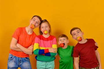 Four children with an apple in their mouths, brothers and sister in bright and colorful clothes advertise a healthy lifestyle and a healthy diet.