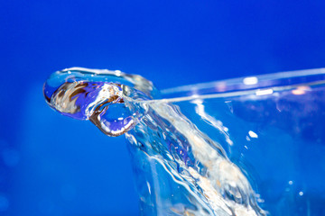Clear water pouring out of the top of a clear glass