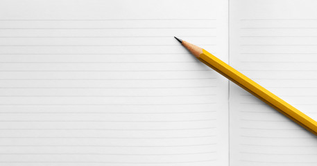 simple orange pencil on a spread of blank pages of a school notebook, concept back to school, study term start