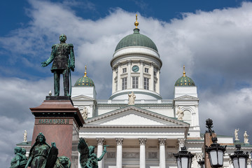 Fototapeta na wymiar Republic of Finland, Helsinki, Senate Square: Panorama view of famous Alexander II statue and Helsinki Cathedral with big green dome, white facade, pillars in the city center of the Finnish capital.