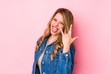 Young caucasian woman isolated on pink background showing rock gesture with fingers