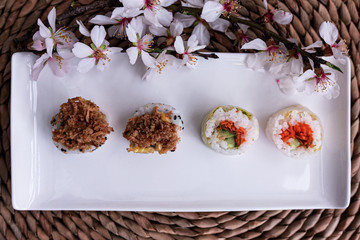 Stock photo of Sushi roll vegetable on white ceramic plate and Sakura flower on wicker surface.