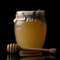 Sweet honey in jar with honey dipper on black background. Organic honey.