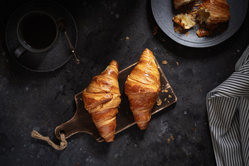 Croissants on a wooden cutting board. Flat lay, top view. Low key