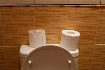 Hygienic paper on a white toilet. On a background of brown tiles.
