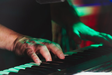 Hands of pianist or keyboardist of a rock band close up playing a synthesizer