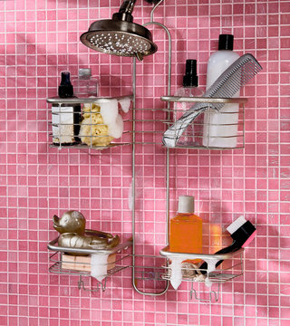 Metal shower caddies hanging in pink tiled bathroom