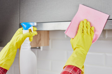 Woman cleaning kitchen. Young woman washing kitchen hood with spray. Close up