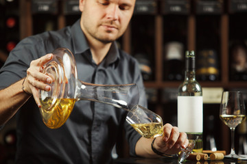 Close up shot of sommelier pours white wine from decanter to the glass