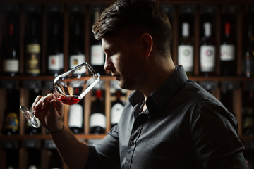 sommelier smells red wine on cellar background, backlight horizontal image.