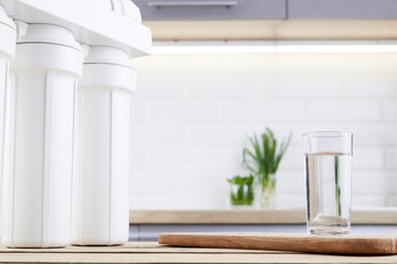 A glass of clean water with osmosis filter on wooden table in kitchen interior