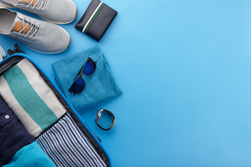 Travel suitcase with clothes on blue background