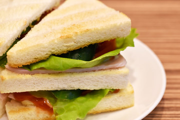 Close-up view, Club sandwich in white dish on wooden table.