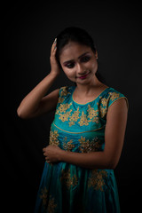 Fashion portrait of an young and attractive Indian Bengali brunette girl in Indian traditional dress in front of a black studio background. Indian fashion portrait and lifestyle.