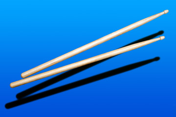 two wooden drumsticks on blue background