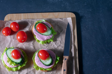 Sandwich with cucumber, lettuce, ham and tomatoes. Sandwiches on a dark background. Selective focus. Healthy food, diet and nutrition concept
