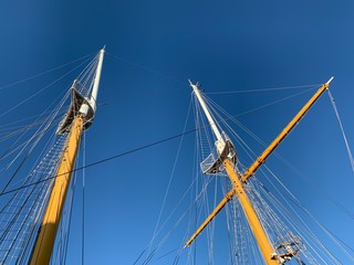 Wooden ship masts in the blue sky background