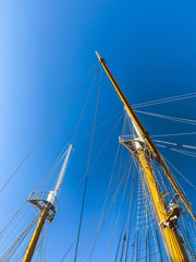Wooden ship masts in the blue sky background