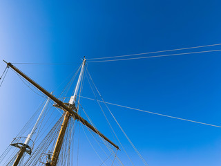 Wooden ship masts in the blue sky background