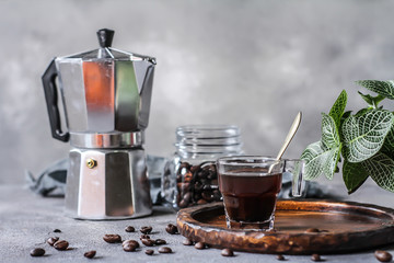 Photo of coffee in glass and beans. Spoon. Coffee pot. Glass cup. On rusty table. Gray background. Woodeen